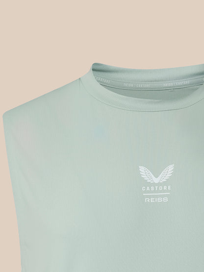 A close-up of a sleeveless ribbed top in a pale mint green color, featuring a white winged logo and the text 'CASTORE REISS' on the left chest, set against a solid beige background.