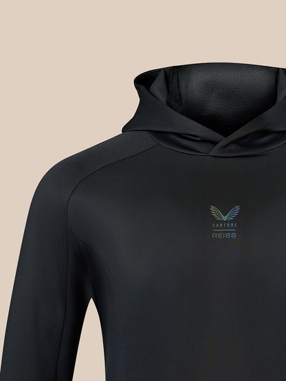 Close-up of a black hooded long-sleeve top with a small winged logo and the text 'CASTORE REISS' on the left chest, shown against a plain beige background.