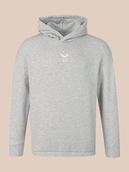A light gray heather pullover hoodie with a small white embroidered logo on the left chest, displayed against a solid beige background.