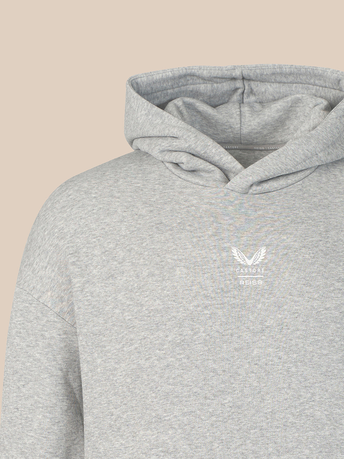 A close-up of a light heather gray hoodie with a small white embroidered winged logo and the text 'CASTORE' and 'B.S.