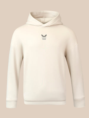 An off-white ribbed pullover hoodie with a small dark gray winged logo and text on the left chest, displayed on a solid beige background.