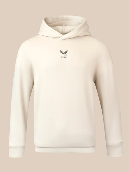 An off-white ribbed pullover hoodie with a small dark gray winged logo and text on the left chest, displayed on a solid beige background.