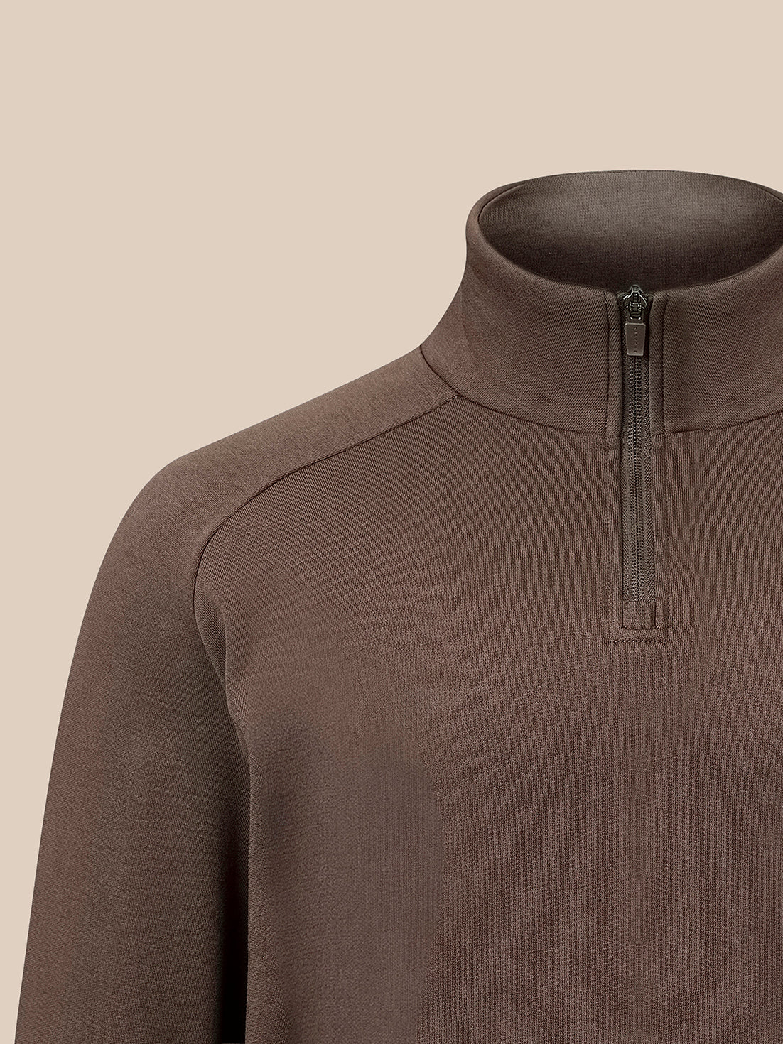 Close-up of a brown quarter-zip mock neck sweater on a mannequin against a solid beige background.