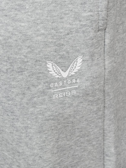 Close-up of a heather gray fabric surface with a small white embroidered winged logo and the text 'CASTORE REISS' centered on the chest.
