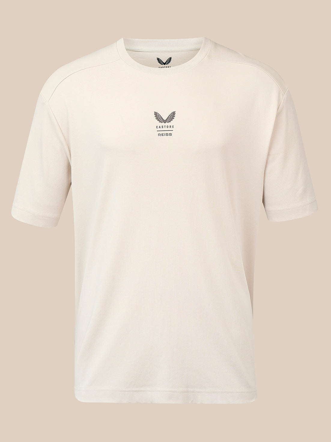 A short-sleeve crewneck athletic t-shirt in off-white, featuring a small dark gray winged logo and the text 'CASTORE' and 'REISS' printed on the centre chest, displayed against a solid beige background.