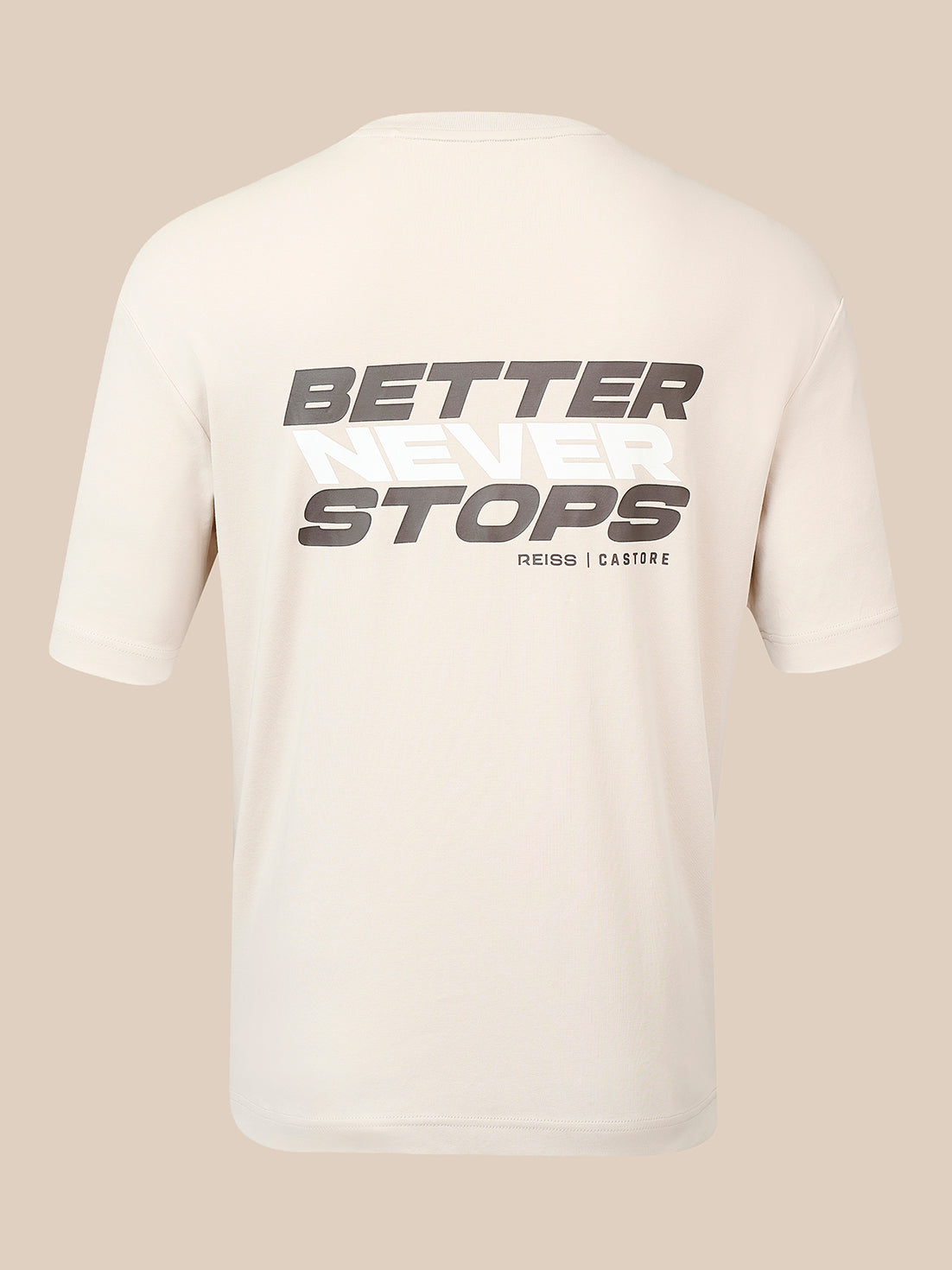 A cream-colored short-sleeve t-shirt shown from the back, featuring a large graphic print that reads 'BETTER NEVER STOPS' in gray and white, with 'REISS | CASTORE' printed below it, set against a solid beige background.