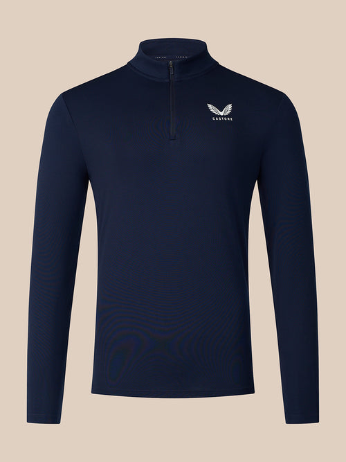 A navy blue long-sleeve quarter-zip pullover with a small white winged logo and the word 'CASTORE' on the left chest, displayed against a solid beige background.