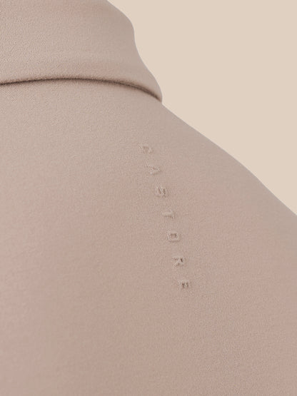 Close-up of a beige or taupe fabric surface with a small vertical debossed wordmark reading 'CASTORE' on the shoulder area.