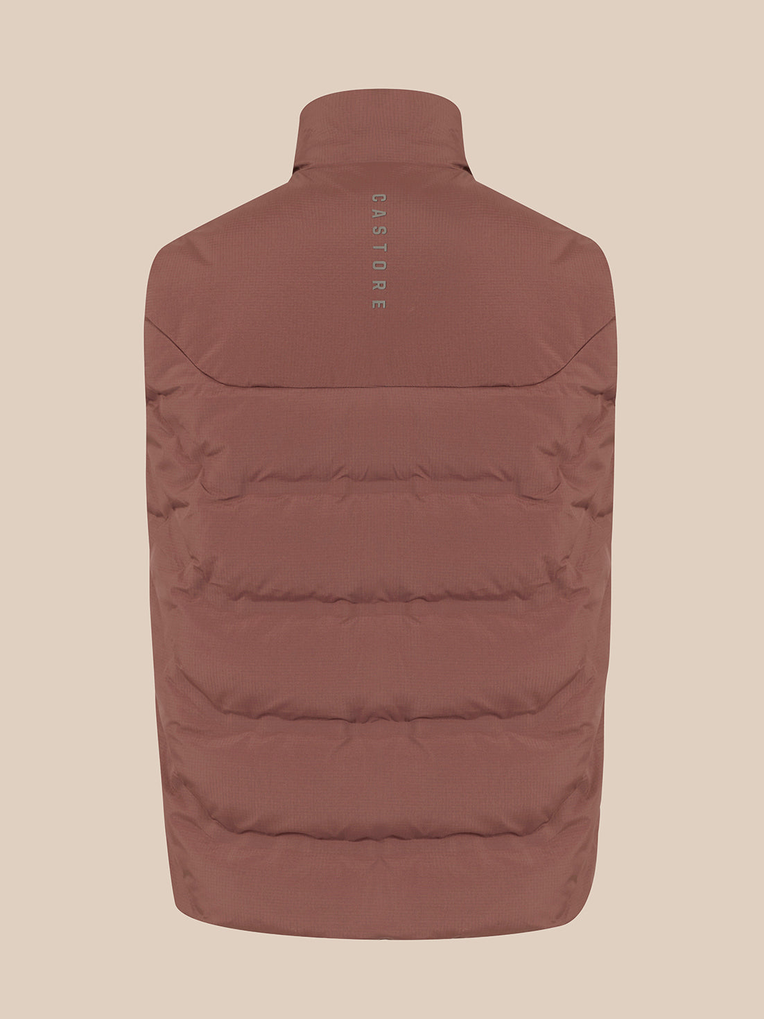 A brown puffer vest shown from the back, featuring horizontal quilting and a small vertical 'CASTORE' logo printed on the upper back, set against a solid beige background.