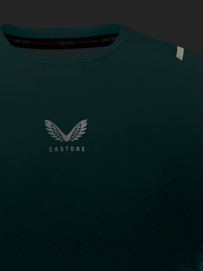 Dark teal Castore t-shirt featuring a white winged logo and the brand name 'CASTORE' printed on the chest, shown against a dark background.