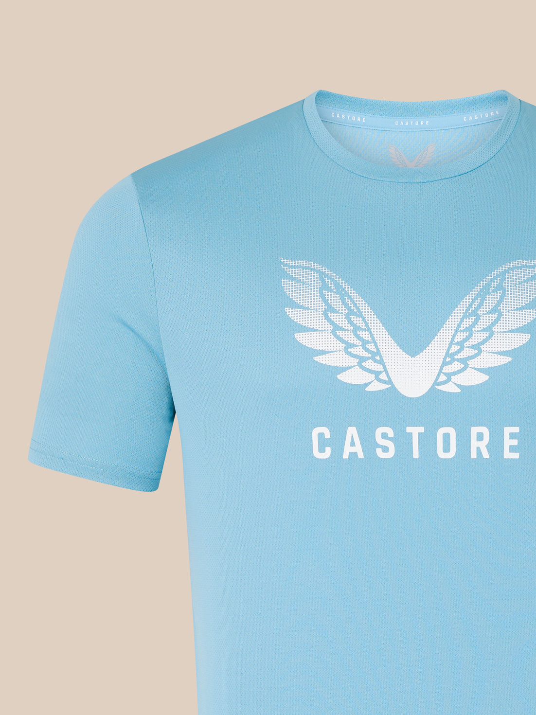 Close up of the blue Wings Graphic T-Shirt chest showing the large white wing logo and CASTORE text.