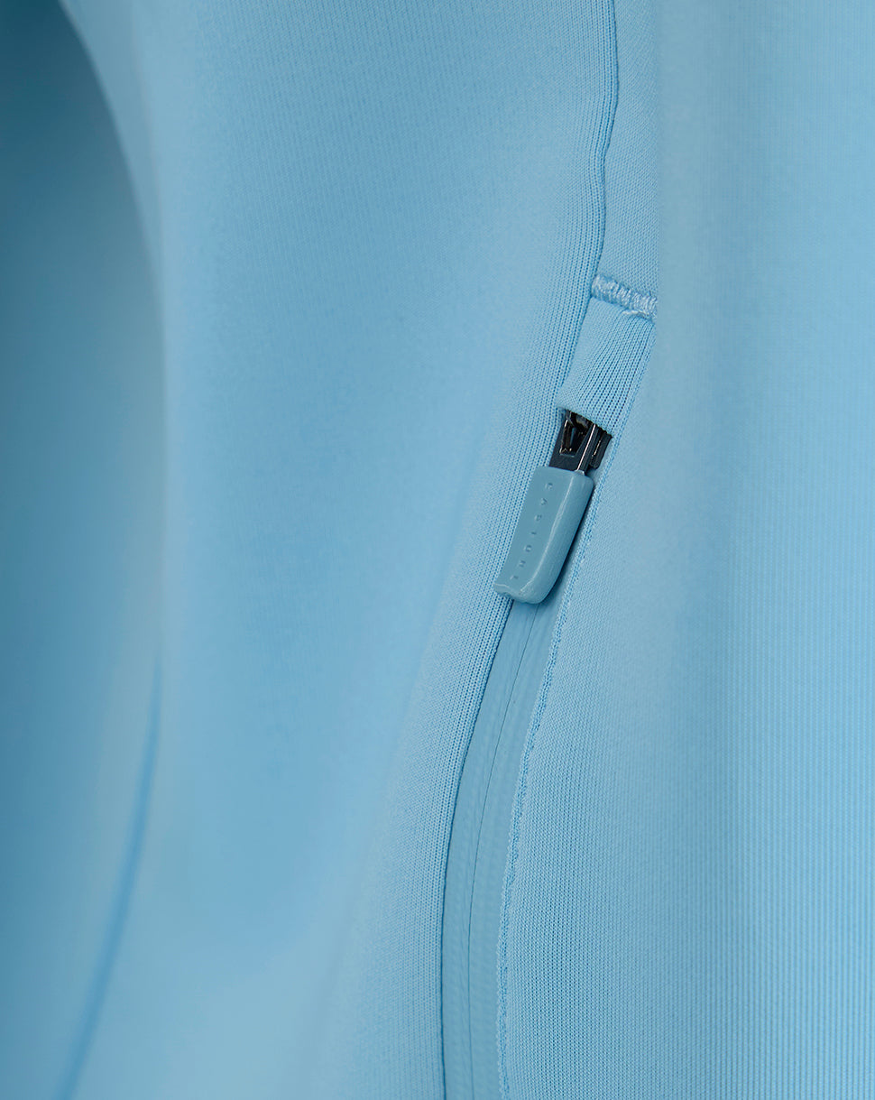 Close-up of side zip pocket with blue zipper pull on the light blue sweatshirt.