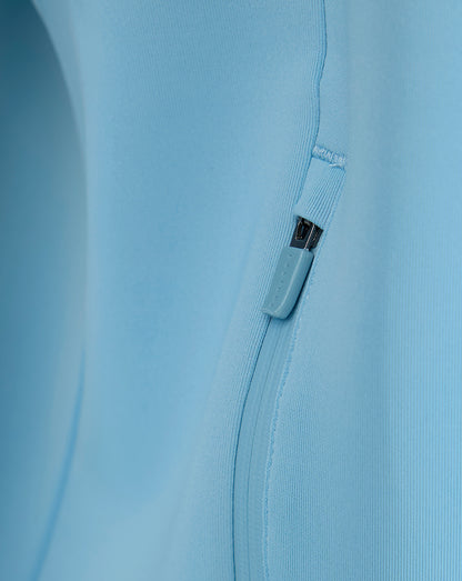Close-up of side zip pocket with blue zipper pull on the light blue sweatshirt.