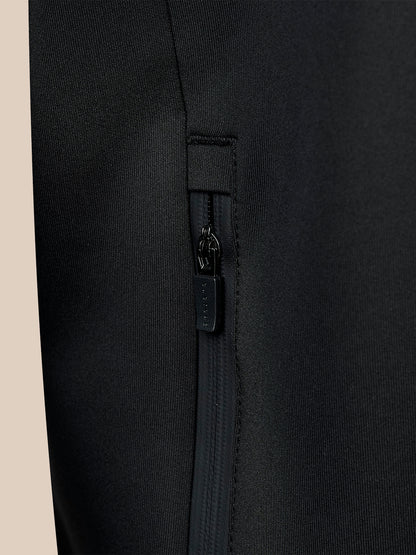 Close-up of black hoodie fabric showing a vertical zippered pocket and branded zipper pull