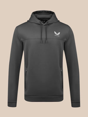 A dark gray pullover hoodie with a drawstring hood and a white winged logo on the left chest, displayed on a solid beige background.