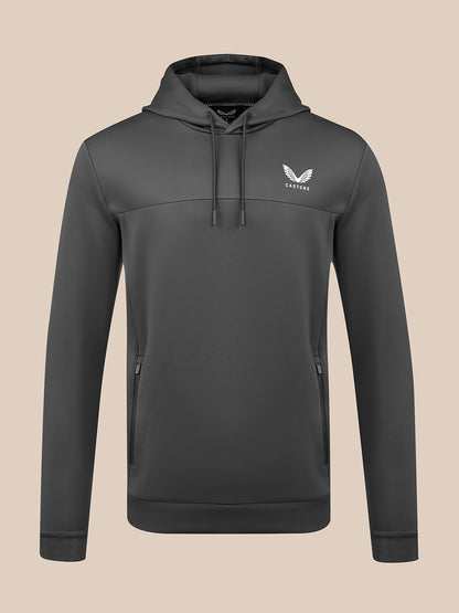 A dark gray pullover hoodie with a drawstring hood and a white winged logo on the left chest, displayed on a solid beige background.