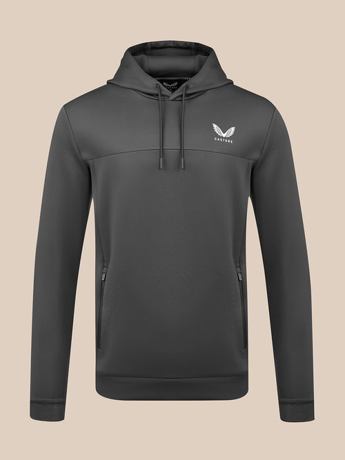 A dark gray pullover hoodie with a drawstring hood and a white winged logo on the left chest, displayed on a solid beige background.