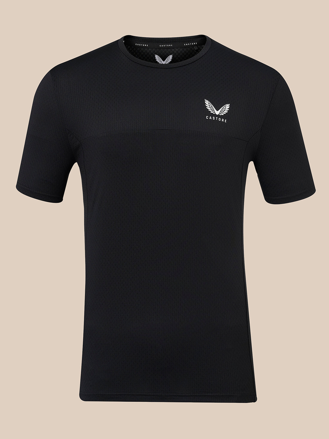 A black short-sleeve athletic t-shirt with a textured knit pattern, featuring a small white wing logo and the brand name 'CASTORE' on the left chest, displayed against a solid beige background.