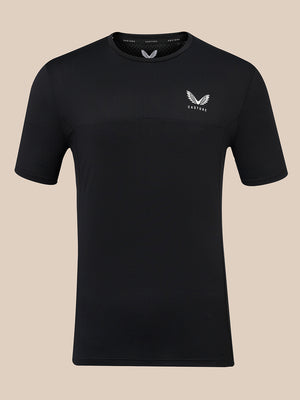 A black short-sleeve athletic t-shirt with a textured knit pattern, featuring a small white wing logo and the brand name 'CASTORE' on the left chest, displayed against a solid beige background.