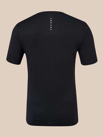 A black short-sleeve athletic t-shirt shown from the back, featuring a vertical white 'CASTORE' brand logo printed on the upper back, set against a solid beige background.