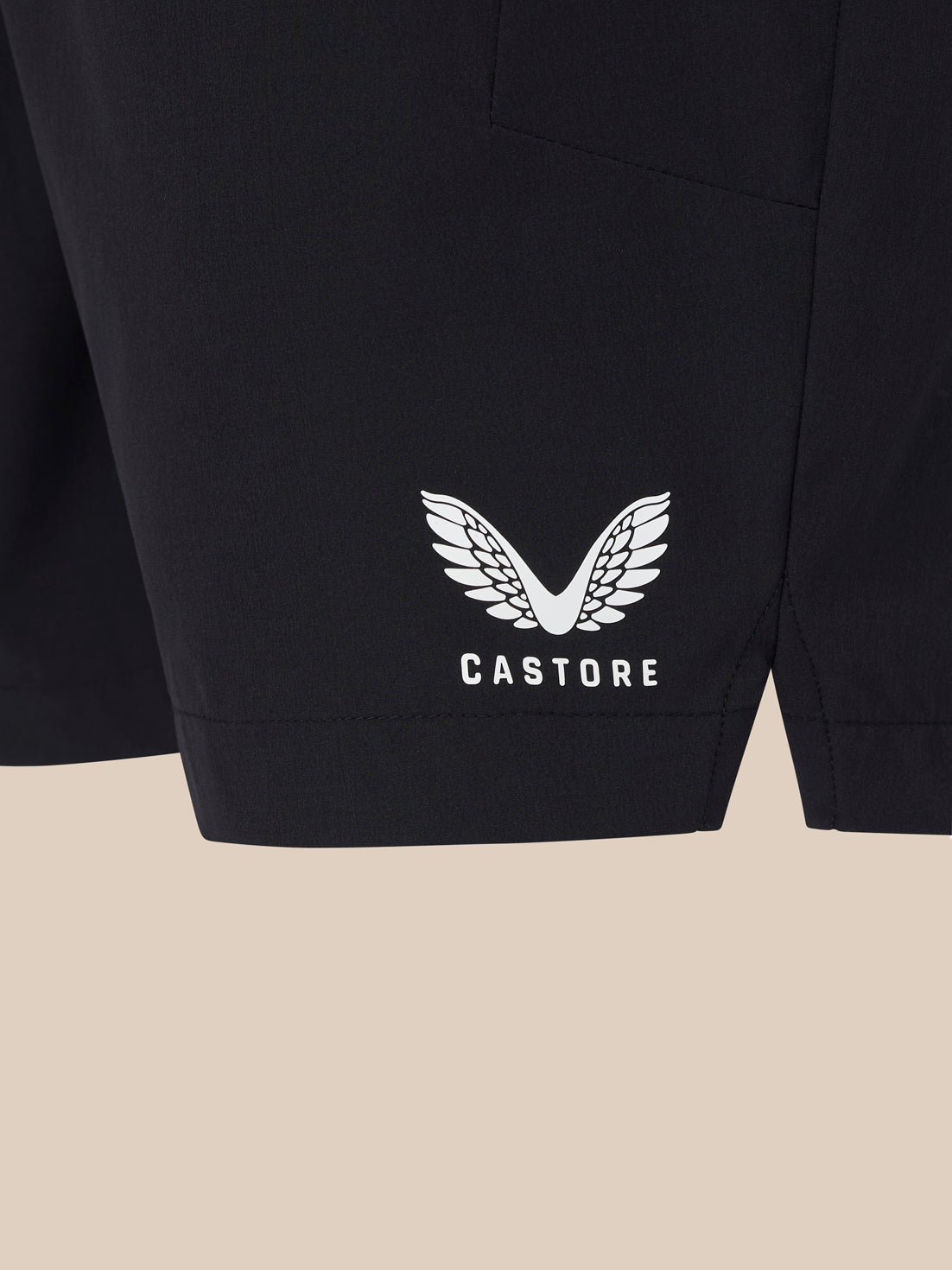 Close up of black shorts lower leg with a white winged Castore logo