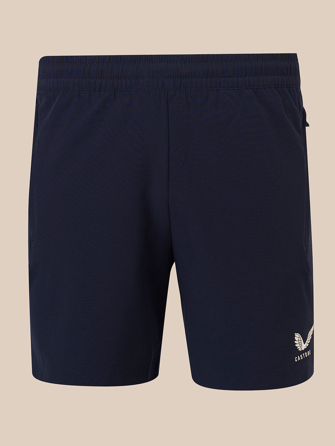 Navy blue athletic shorts with an elastic waistband and a small white embroidered logo on the lower left leg, shown against a solid beige background.