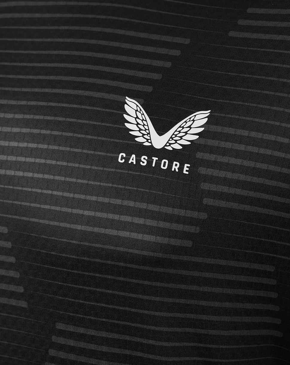 Close-up of white Castore winged logo on black fabric with horizontal stripe pattern