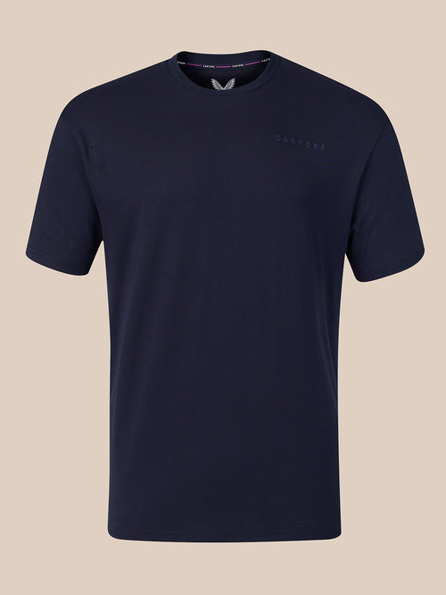 A dark navy blue crew-neck t-shirt with a subtle tonal embroidered logo on the left chest, displayed against a solid beige background.