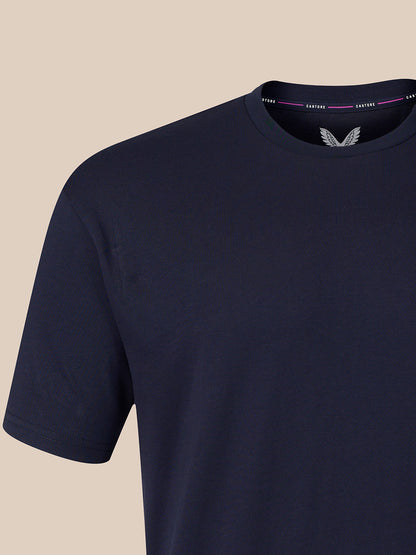 A close-up of a navy blue short-sleeve crewneck t-shirt, showing the inner collar with a white wing logo and the brand name CASTORE.