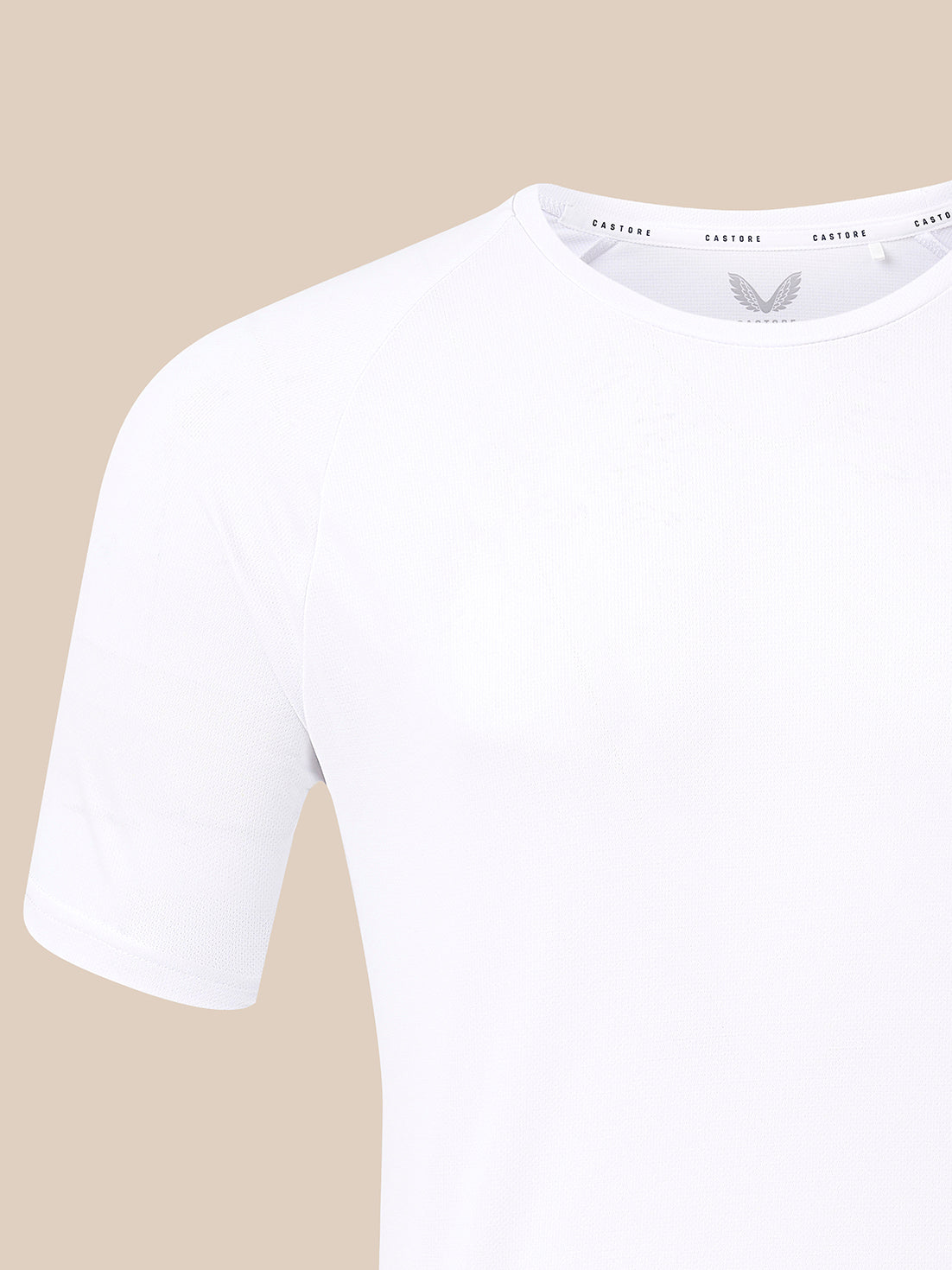 A close-up of a white short-sleeve crewneck t-shirt on a solid beige background.