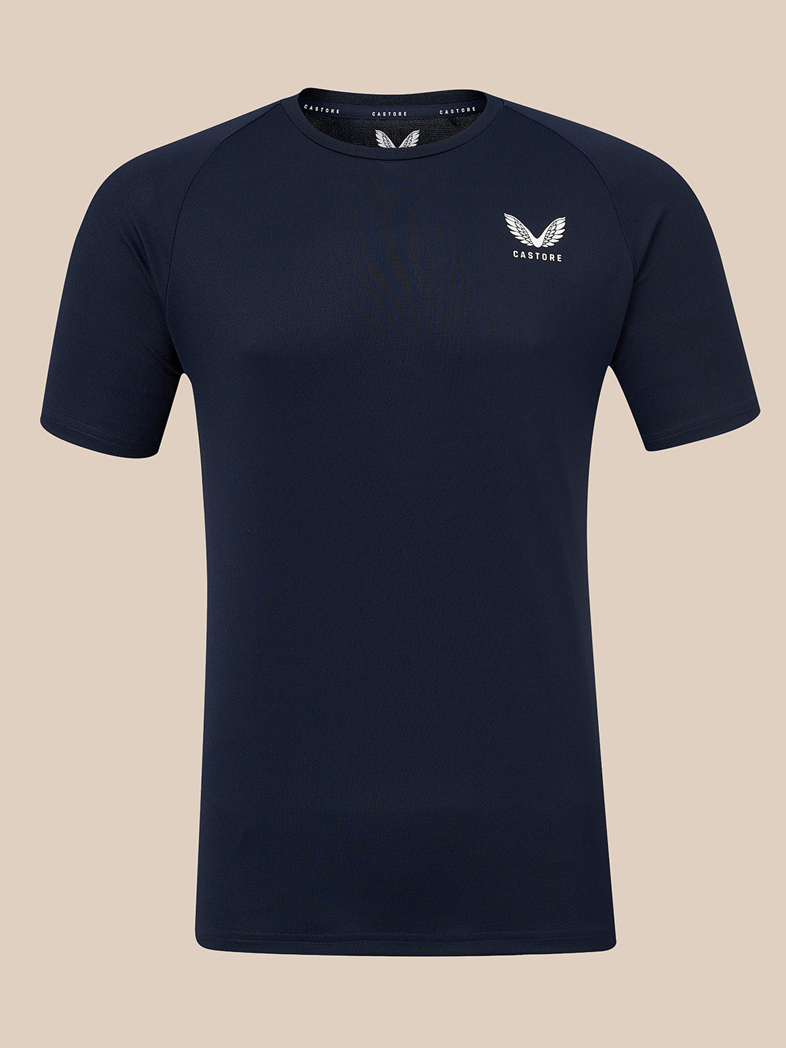 A dark navy blue short-sleeve athletic t-shirt with a white winged logo and the brand name 'CASTORE' printed on the left chest, displayed against a solid beige background.