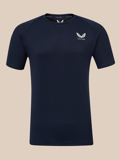 A dark navy blue short-sleeve athletic t-shirt with a white winged logo and the brand name 'CASTORE' printed on the left chest, displayed against a solid beige background.