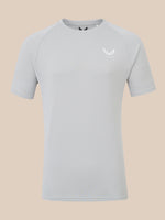 A light gray short-sleeve athletic t-shirt with a small white wing logo and the brand name 'CASTORE' printed on the left chest, displayed against a solid beige background.