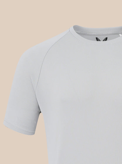 A close-up of a light gray short-sleeve athletic t-shirt with raglan sleeves, shown against a solid beige background.