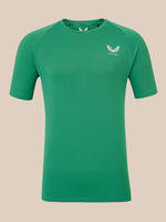 A green short-sleeve athletic t-shirt with a white winged logo on the left chest reading 'CASTORE', displayed against a solid beige background.