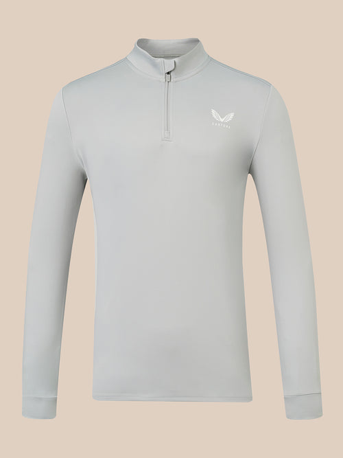 A light gray long-sleeve quarter-zip pullover with a small white wing logo on the left chest, displayed on a solid beige background.