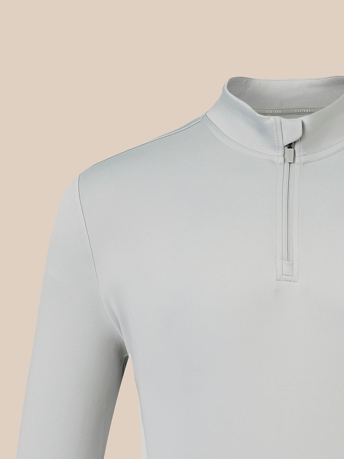 Close-up of a light gray long-sleeve quarter-zip pullover top on a mannequin, showing the collar, zipper, and shoulder against a solid beige background.