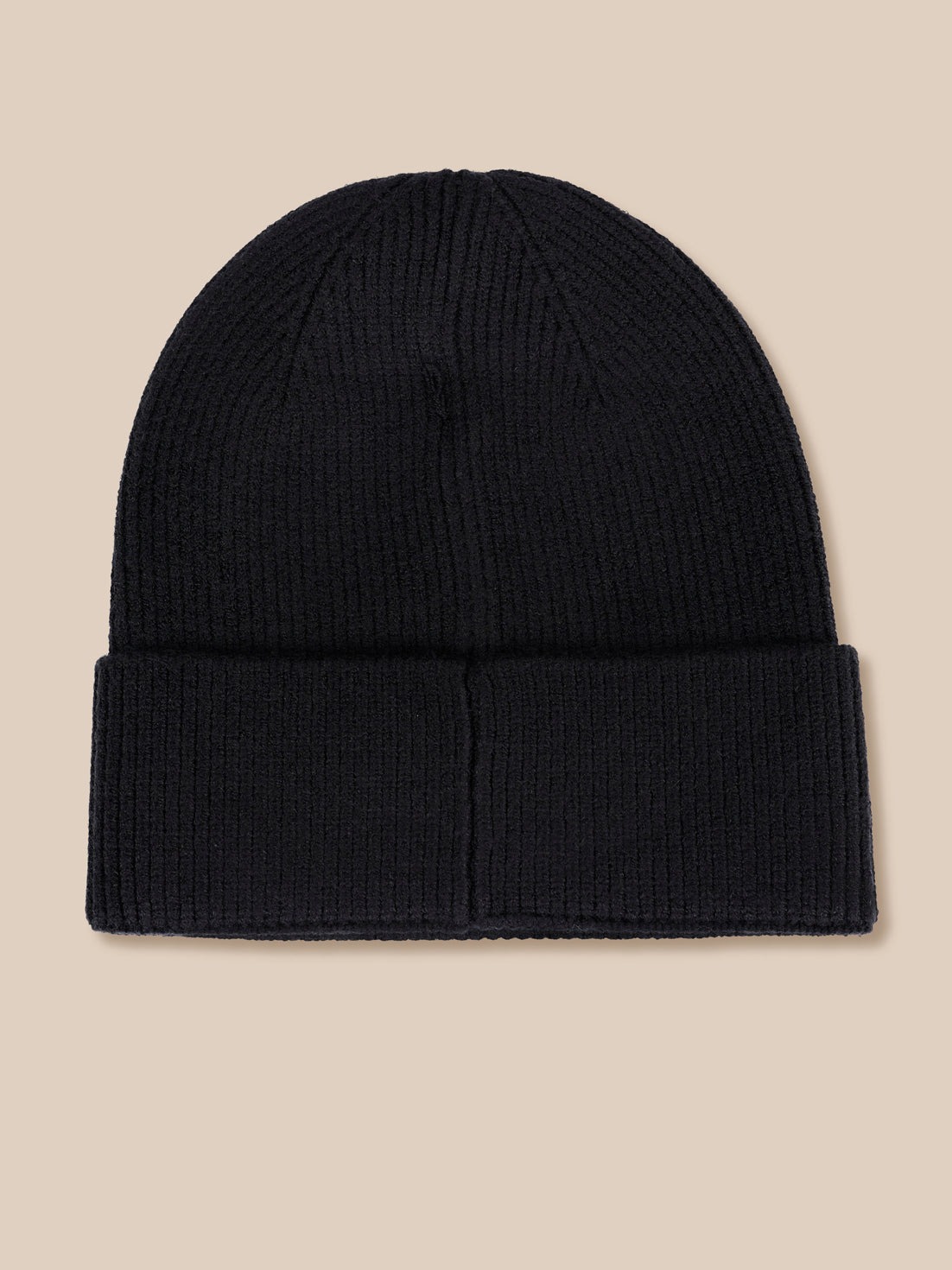 A black ribbed knit beanie hat with a folded cuff, shown flat against a solid beige background.