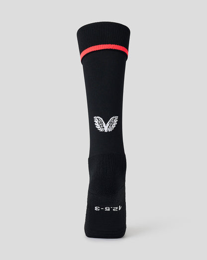 A single black athletic crew sock with a bright red band near the cuff, a white wing logo in the center, and white text near the foot, shown against a light gray background.