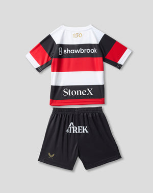 A kids' rugby-style jersey and shorts set laid flat on a light gray background. The jersey is white with bold black and red horizontal stripes, short sleeves, and sponsor logos including Shawbrook and StoneX.