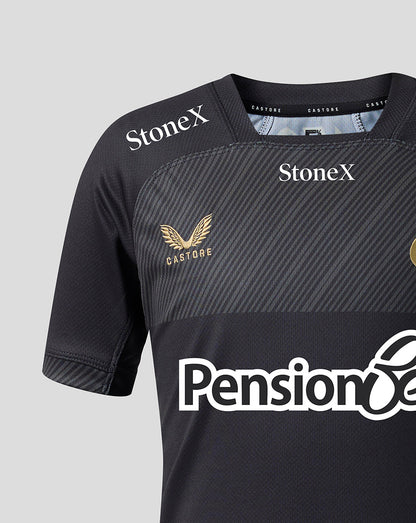 Close-up of a dark gray athletic jersey with diagonal textured stripes, featuring 'StoneX' logos on the shoulders, a gold winged eagle crest with 'CASTORE' on the chest, and a white 'Pension' sponsor logo across the lower front.