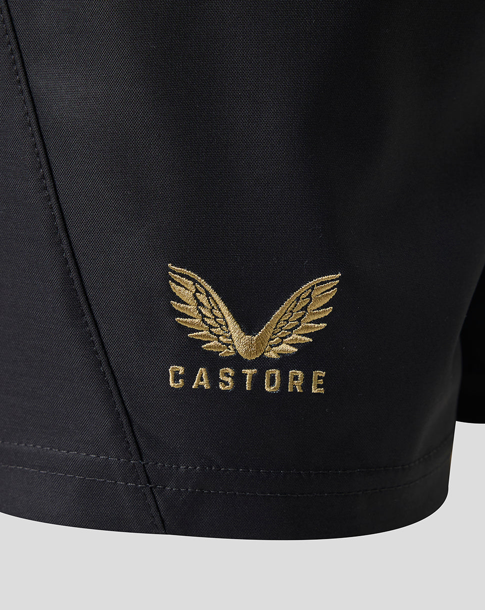 Close-up of black athletic shorts with a gold embroidered winged logo and the word CASTORE on the left leg.