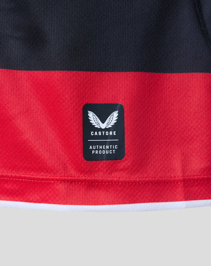 Close-up of a red and black athletic garment showing a black Castore brand patch with a white wing logo and 'AUTHENTIC PRODUCT' text.