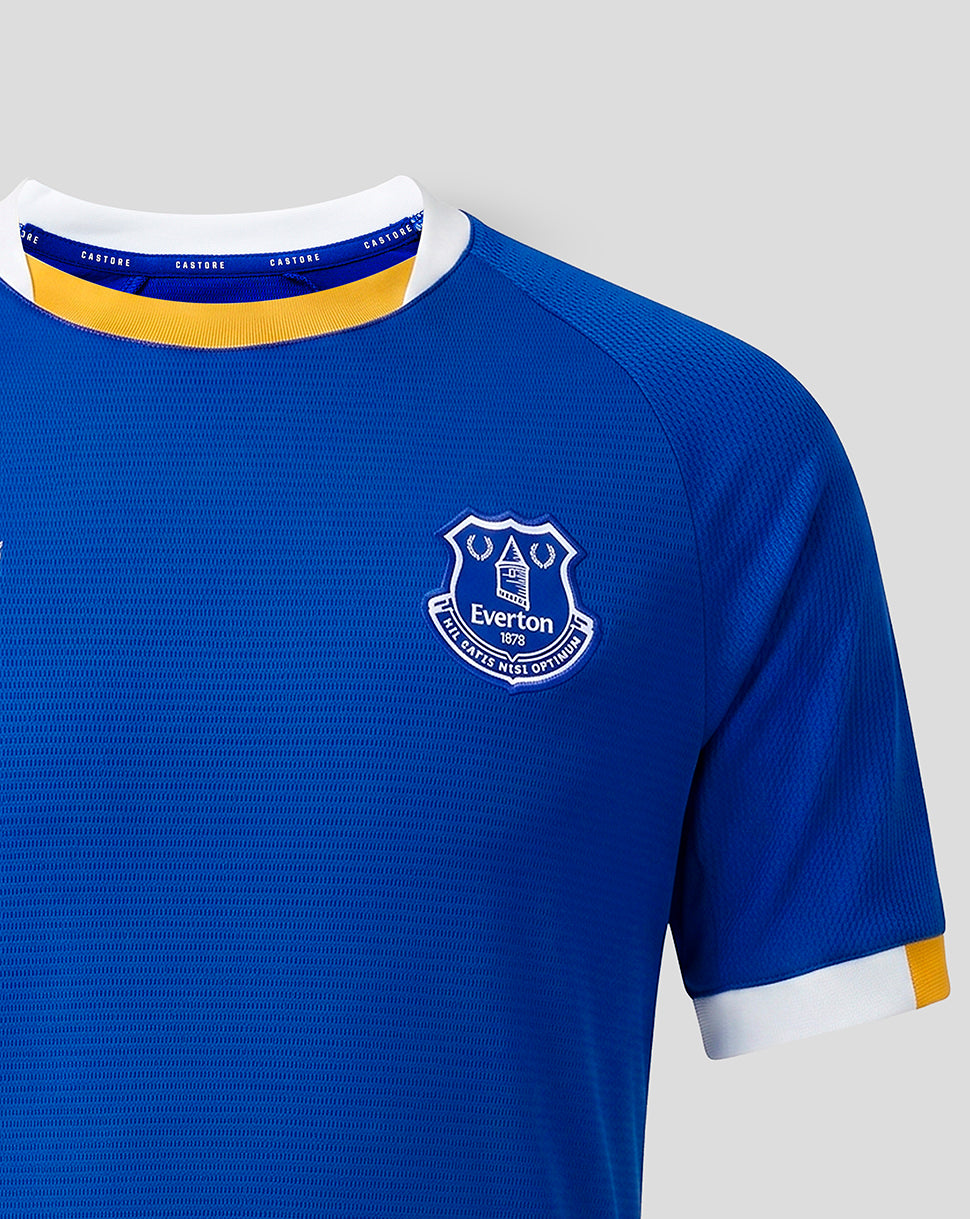 Close-up of the Everton junior home shirt chest crest and sleeve cuff detailing in blue with white and yellow trim