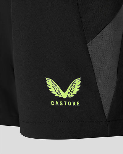 Close-up of a black athletic garment showing a bright neon green Castore wing logo and brand name on the lower front, with a dark gray side panel.