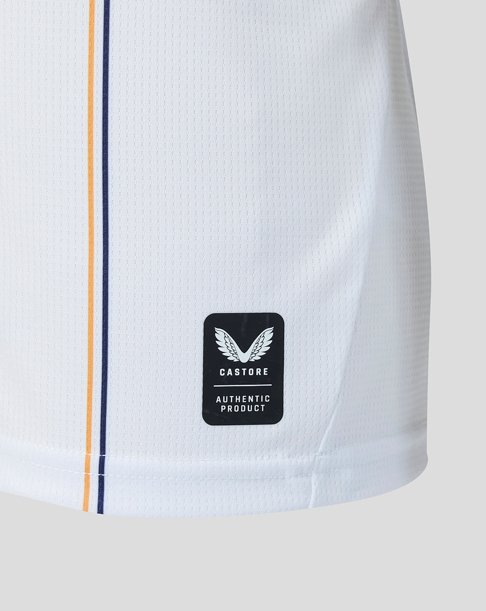 Close up of white jersey hem showing Castore authentic product badge and navy orange piping