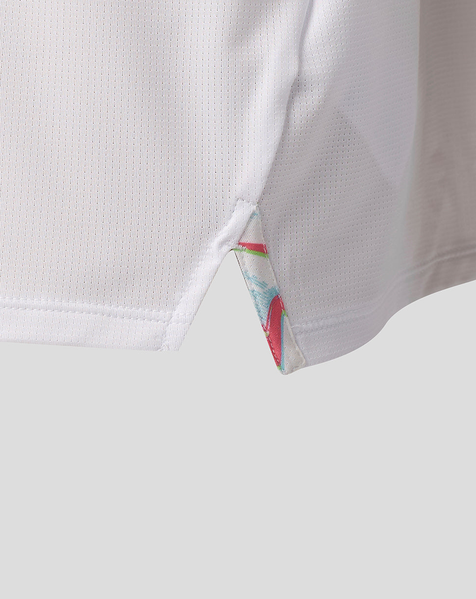 Close-up of side hem on a white Harlequins junior matchday shirt showing a triangular vent and colorful trim.