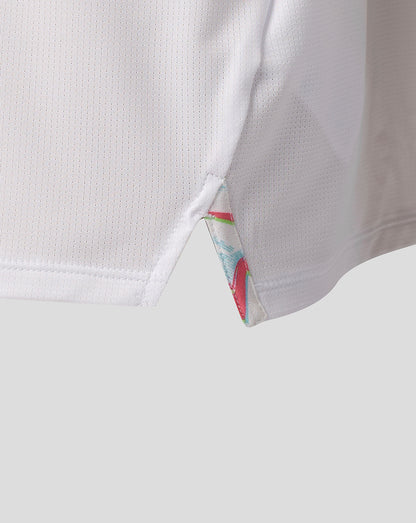 Close-up of side hem on a white Harlequins junior matchday shirt showing a triangular vent and colorful trim.