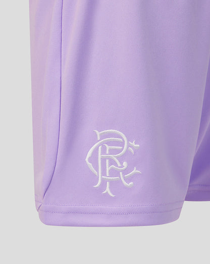 Close-up of a lavender athletic shorts leg featuring an embroidered white monogram logo near the hem, set against a solid light gray background.