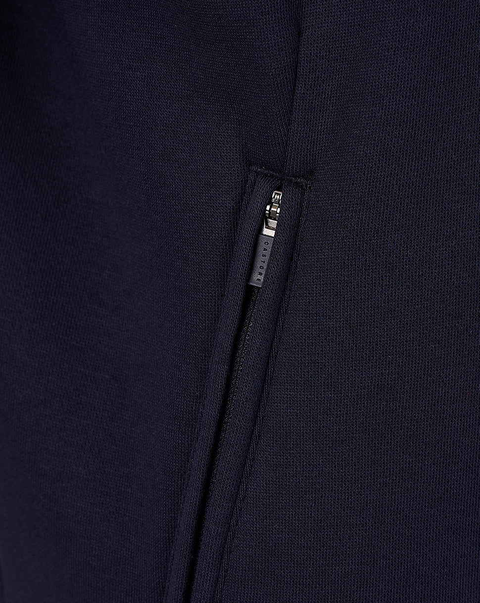 Close-up of navy travel sweatshirt fabric with a vertical side zip pocket and Castore zipper